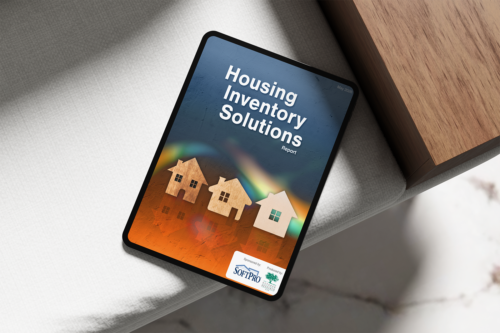 Tablet displaying the cover of a the “Housing Inventory Solutions” report, featuring house icons over an orange-to-blue background.