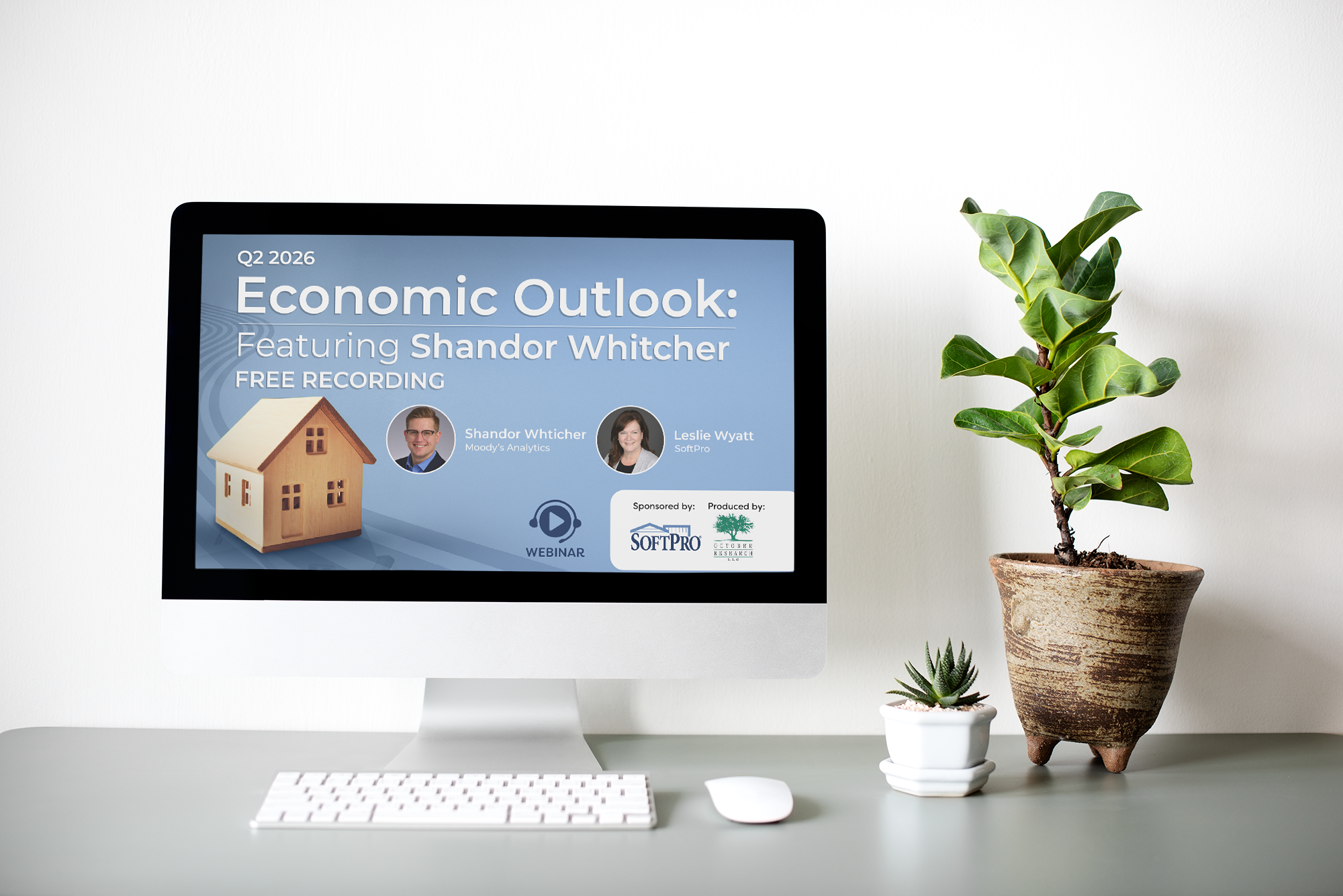 A computer monitor on a desk displays a promotional webinar slide reading “Q2 2026 Economic Outlook: Featuring Shandor Whitcher – Free Recording,” featuring speaker headshots, a small house graphic, and sponsor logos.