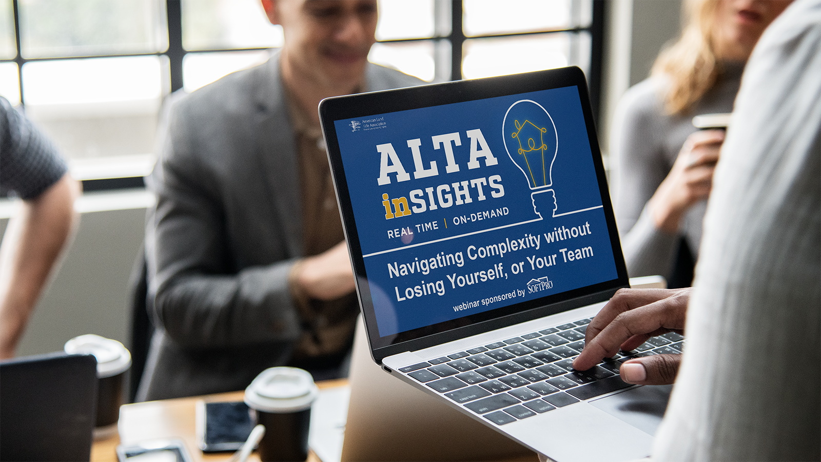 A group gathers around a laptop displaying an ALTA Insights webinar titled "Navigating Complexity Without Losing Yourself, or Your Team," sponsored by SoftPro.